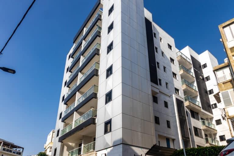חזית בניין יוקרה בישראל בחיפוי לוחות אלומיניום בגוון כהה בשיטת חזית מאווררת. עיצוב מינימליסטי עם קווים נקיים והתקנה נסתרת של חברת פסאדטק